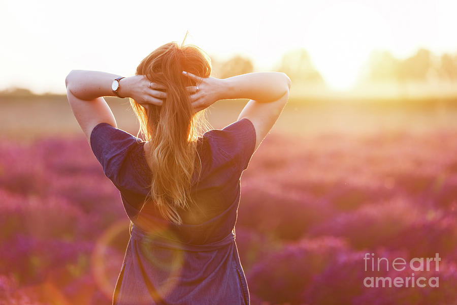 Young woman touching her long sombre hair looking at lavender field at sunset Photograph by Michal Bednarek