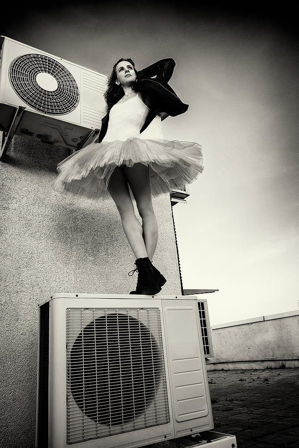 A Ballerina In Tutu, Jacket And Boots Climbed On The Air Conditioner And Poses Against The Sky #1 Photograph by Alexandr
