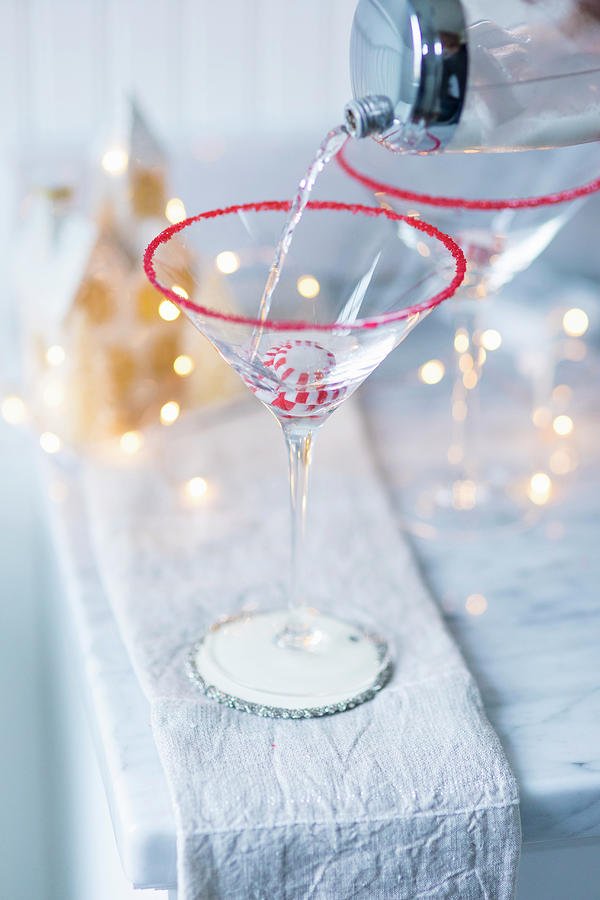 A Drink Being Poured Into A Martini Glass Over A Christmas Bonbon #1 Photograph by Eising Studio