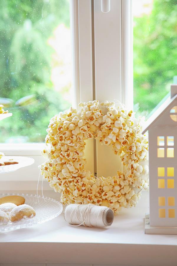 A House-shaped Candle Lantern, A Popcorn Wreath And A Tiered Cake Stand Of Biscuits #1 Photograph by Studio Lipov