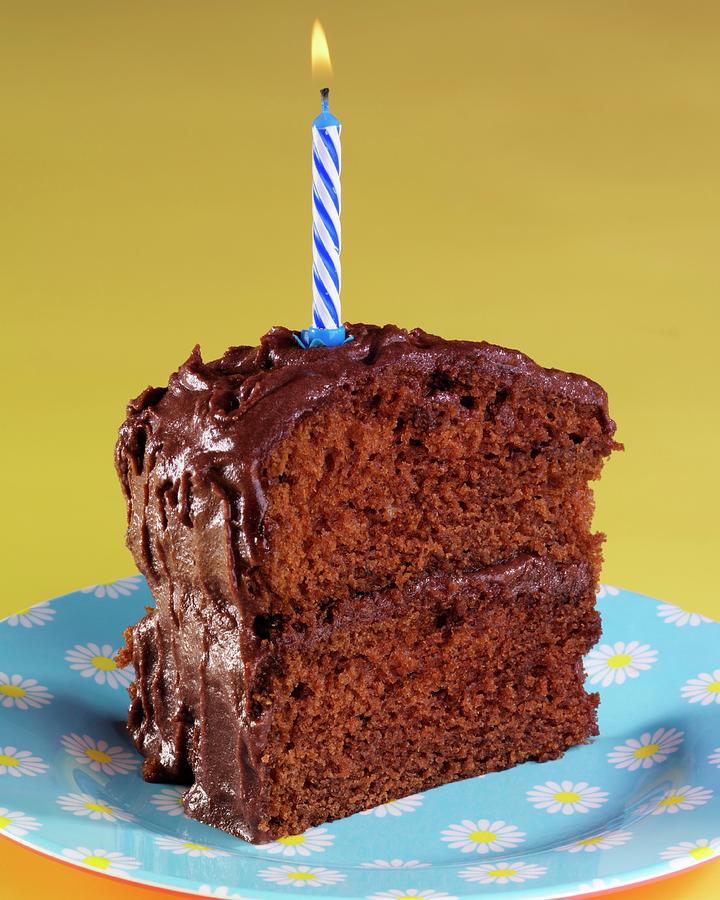 A Slice Of Devils Food Cake chocolate Layer Cake, Usa With A Birthday Candle Photograph by Foodfolio