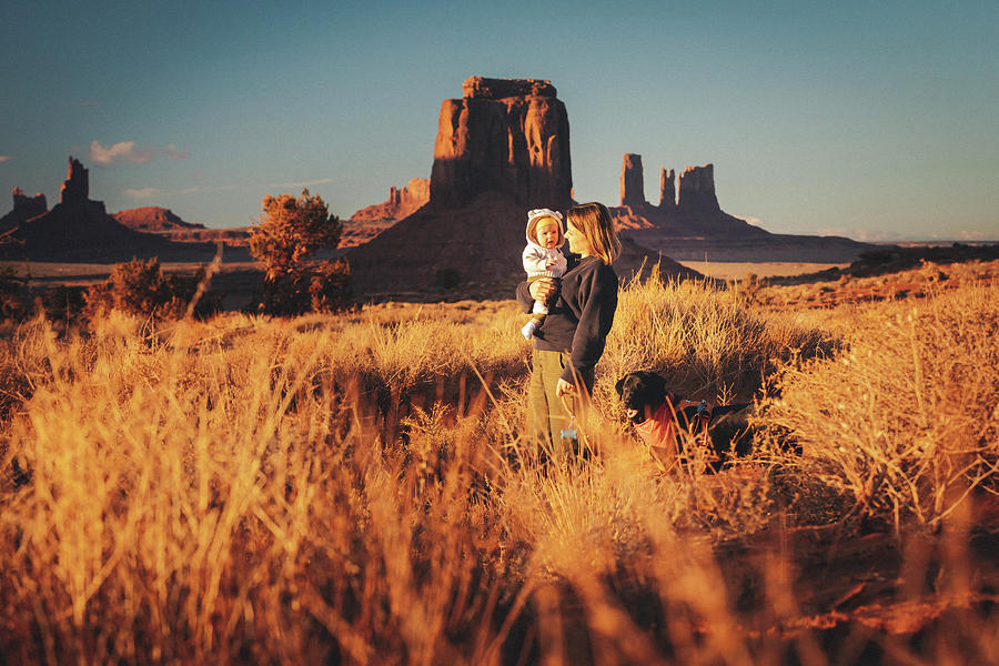 Nature Photograph - A Woman With A Baby And A Dog Is Standing In Monument Valley, Arizona #1 by Cavan Images