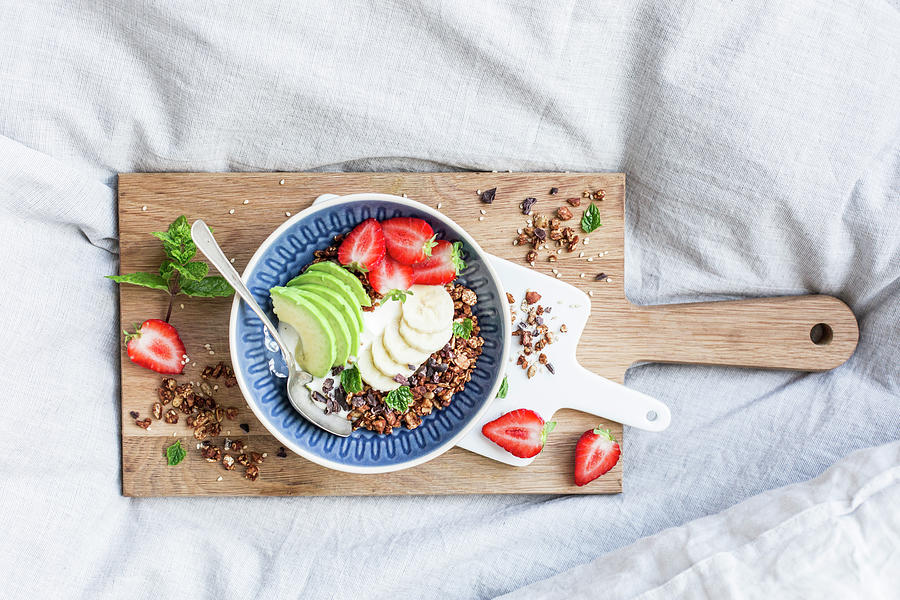 Almond And Sesame Seed Granola With Strawberries And Avocado On A Wooden Board On A Bed #1 Photograph by Theveggiekitchen