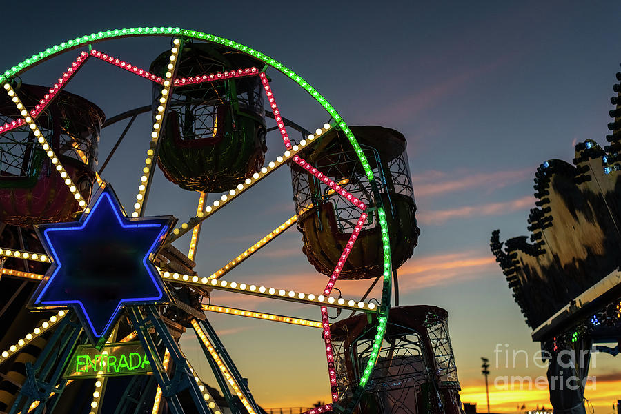 Amusement park at dusk with ferris wheel in the background. #1 Photograph by Joaquin Corbalan