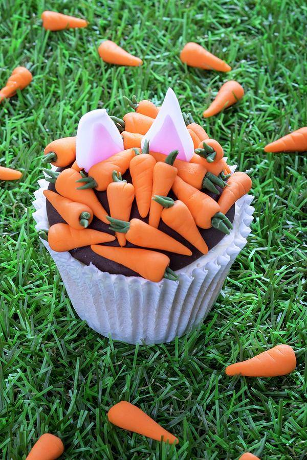 An Easter Cupcake Decorated With Carrots And Rabbit Ears #1 Photograph by Adrian Britton
