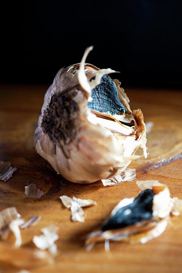 Black Garlic On A Wooden Table #1 Photograph by Jamie Watson