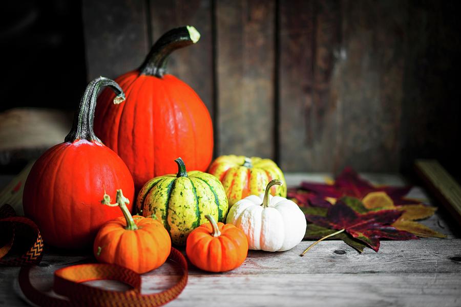 Bright Pumpkins And Autumn Leaves On Rustic Wooden Surface #1 Photograph by Alena Haurylik