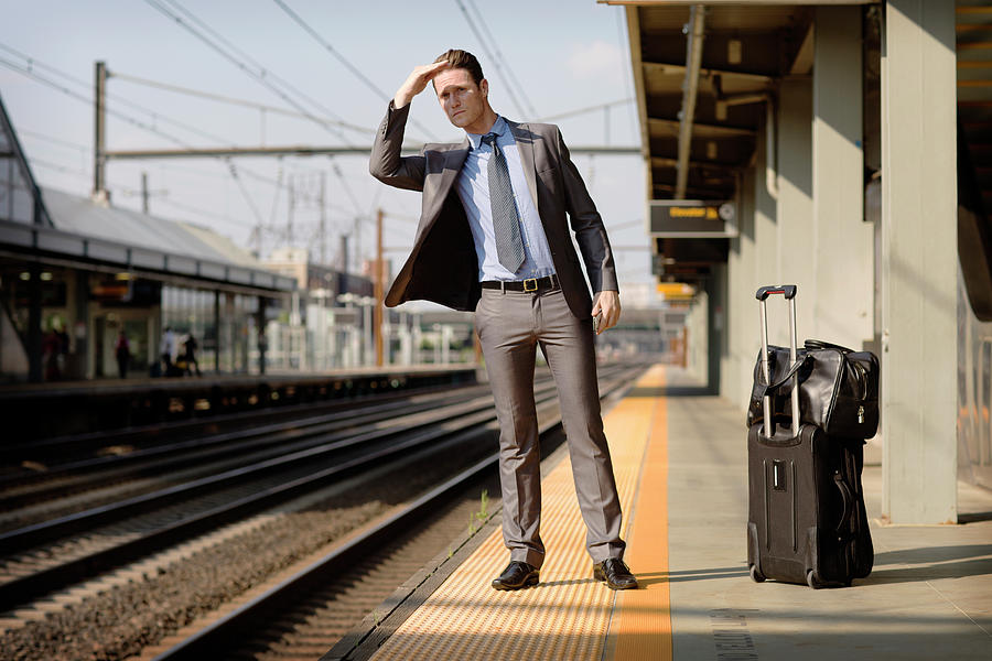 Transportation Photograph - Businessman Shielding Eyes While Waiting At Railway Platform #1 by Cavan Images