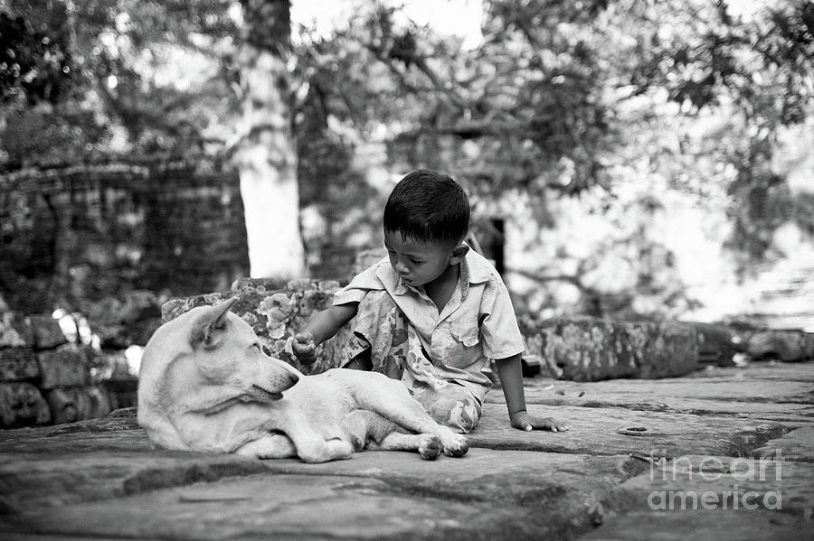 Cambodian boy near some ruins playing with his dog. #1 Photograph by Joaquin Corbalan