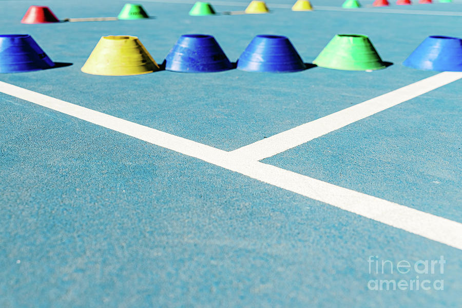 Colorful plastic cones on a blue cement tennis court with white  #1 Photograph by Joaquin Corbalan