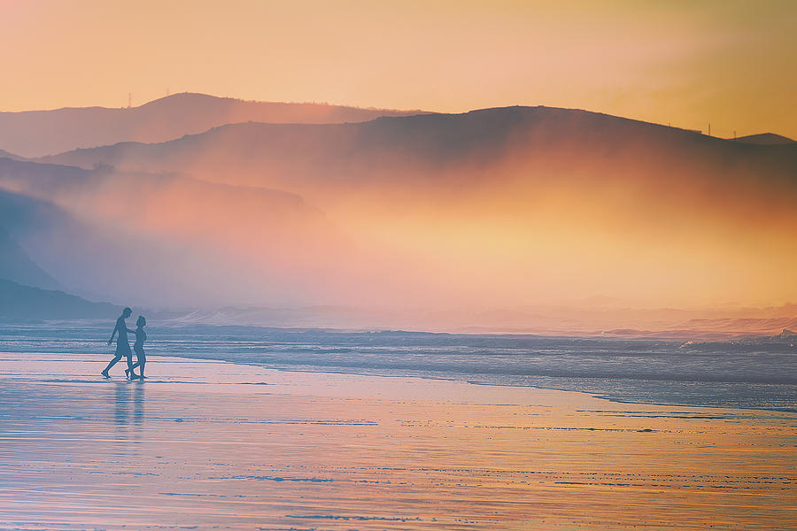 Couple Walking On Beach At Sunset #1 Photograph by Mikel Martinez de Osaba