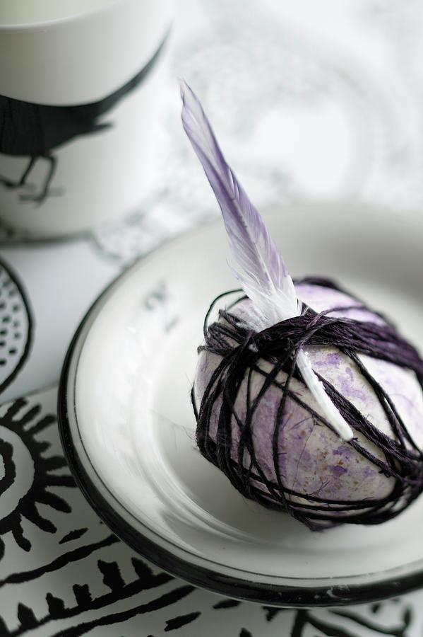 Easter Egg Painted Purple Wrapped In Cord And Decorated With Feathers On Plate #1 Photograph by Bjarni B. Jacobsen