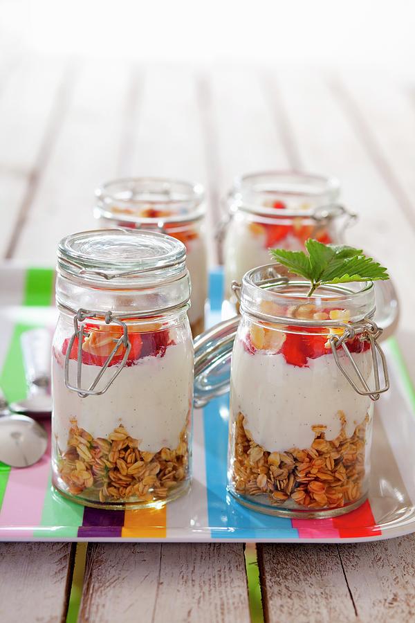 Four Jars Containing Ingredients For Muesli: Rolled Oats, Vanilla Yoghurt And Strawberries #1 Photograph by Studio Lipov