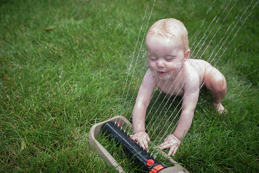 High Angle View Of Naked Baby Boy Playing With Sprinkler On Grassy Field In Yard Photograph By