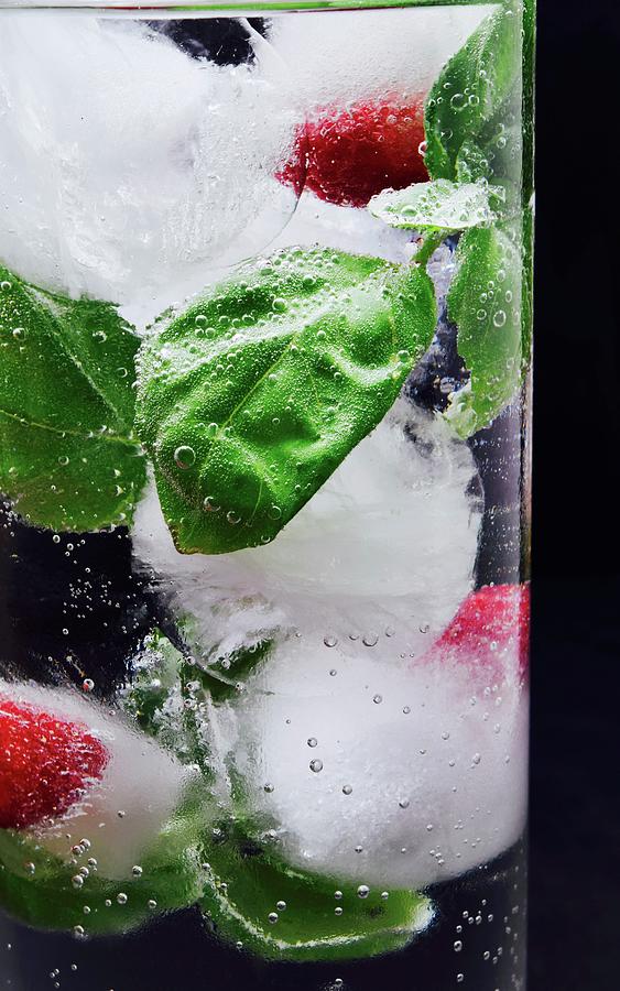 Ice Cubes With Raspberries And Basil In A Glass Of Water #1 Photograph by Elli Briest