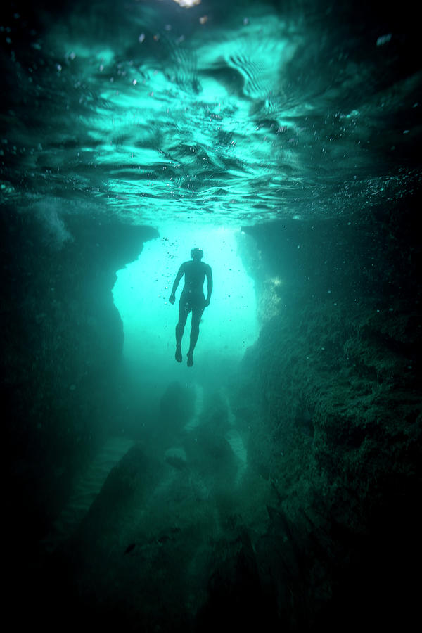 In The Sea, A Man Floats In Apnea Just Under The Surface Of The Water 