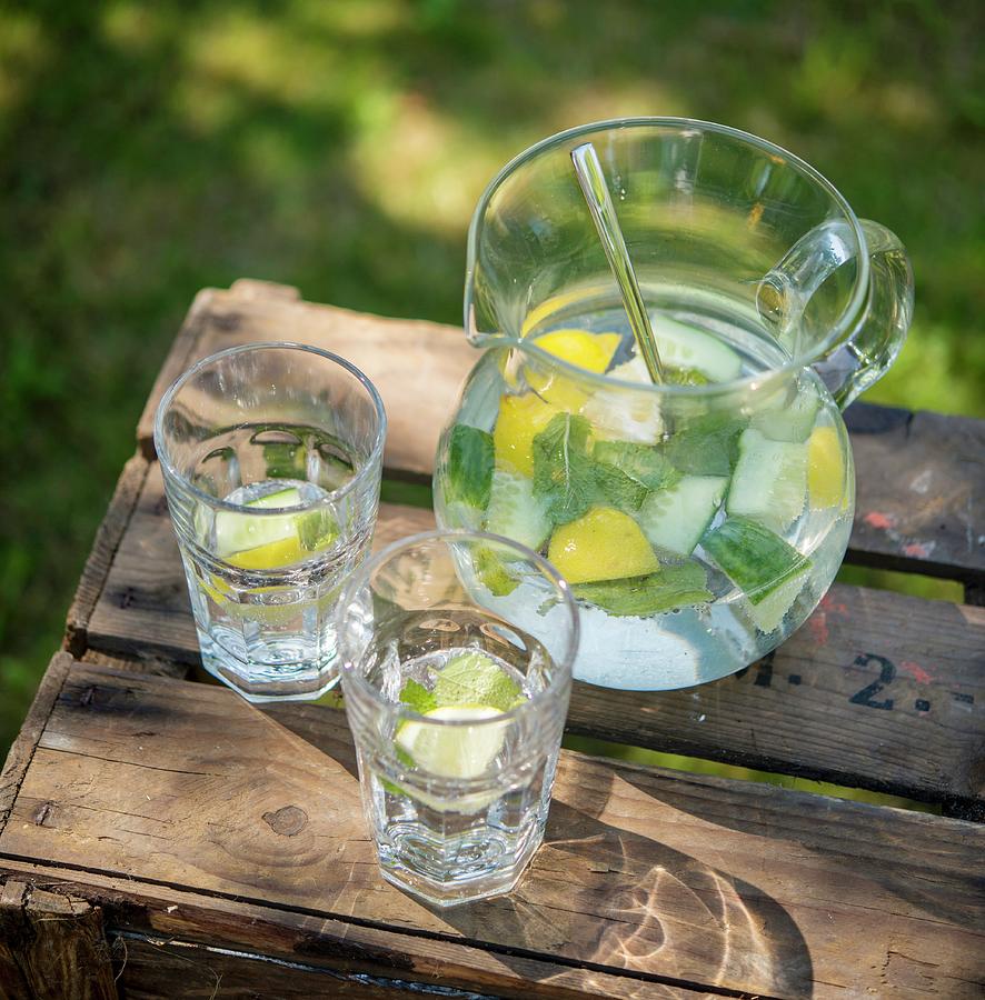 Lemon Water With Cucumber And Mint On A Wooden Crate In The Garden #1 Photograph by Sebastian Schollmeyer