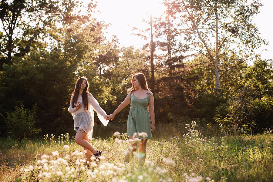 Lesbian Couple Holding Hands While Walking In Forest In Summer