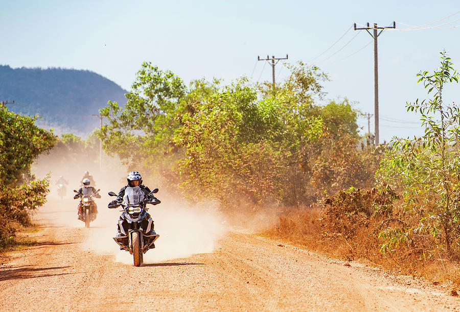 Rural Scene Photograph - Men Riding Their Adventure Motorbikes On Dusty Road In Cambodia #1 by Cavan Images