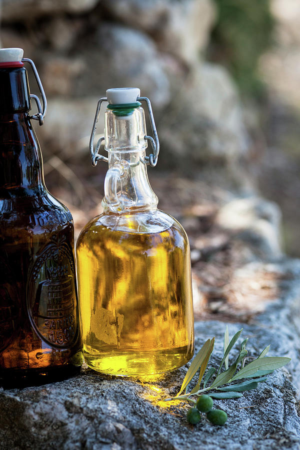 Olive Oil In A Bottle On A Stone Wall #1 Photograph by Eising Studio