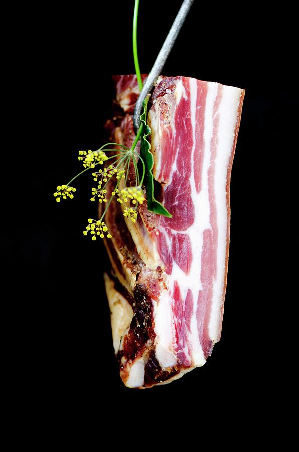 Pancetta Hanging On A Butchers Hook With Fresh Italian Herbs #1 Photograph by Jamie Watson