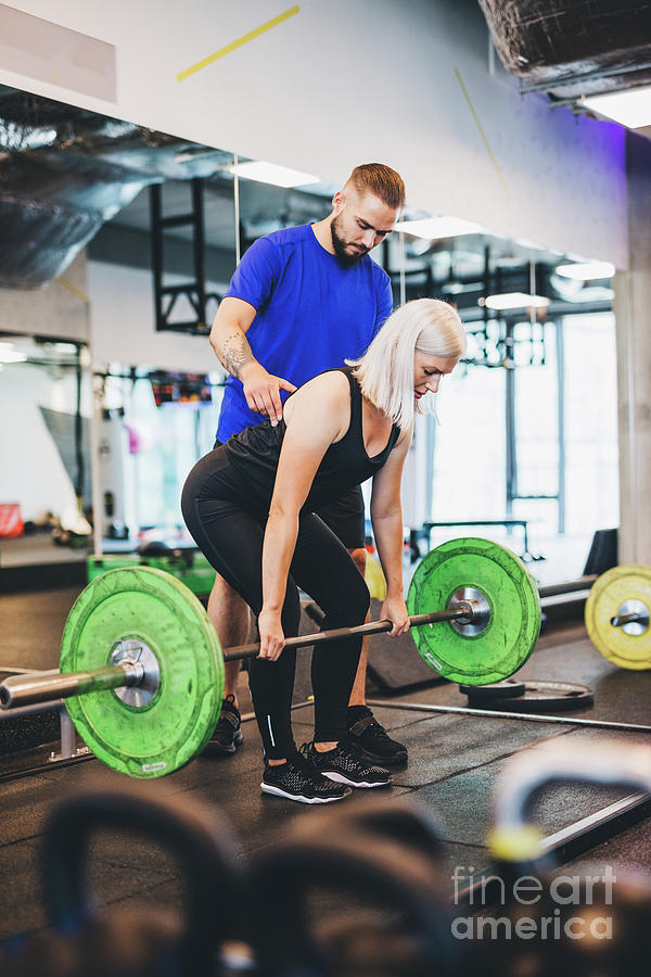 Personal Trainer Assisting Woman Lifting Weights. Photograph