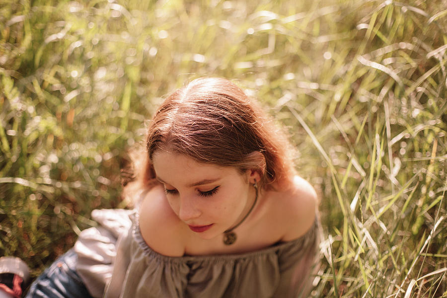 Portrait Of Teenage Girl Sitting On Field In The Grass During Summer ...