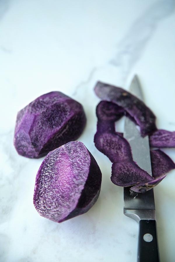 Purple Potatoes, Cut And Peeled With Knife On A White Marble Background #1 Photograph by Andre Baranowski