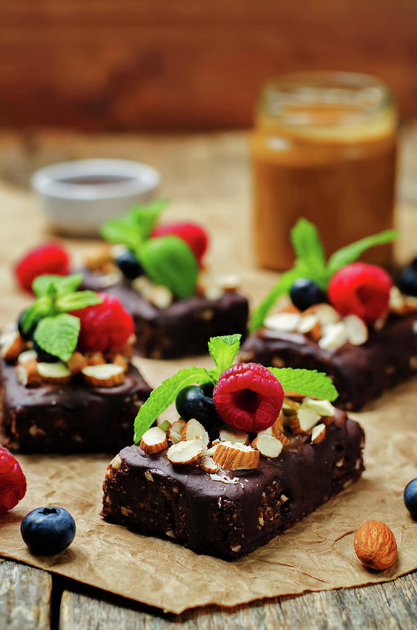 Raw Vegan No Bake Chocolate, Dates And Almond Brownies With Chocolate Frosting And Berries #1 Photograph by Natasha Arz