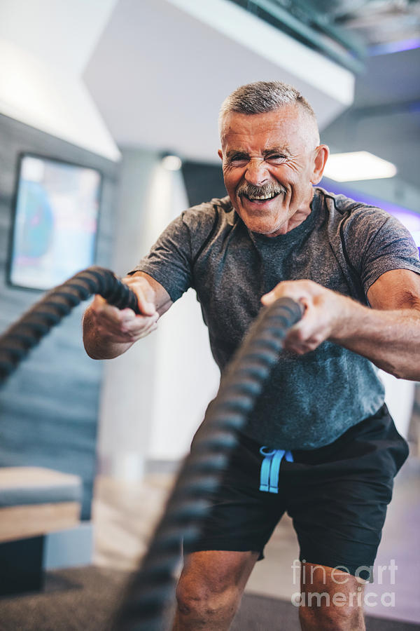 Senior Man Exercising With Ropes At The Gym. Photograph