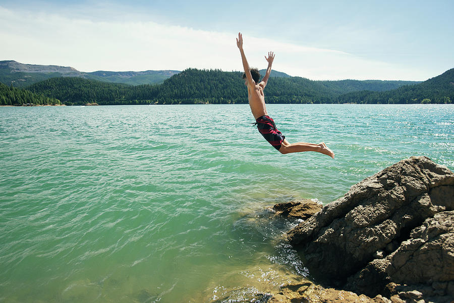 Side View Of Boy Jumping Into Lake Against Sky Photograph by Cavan ...