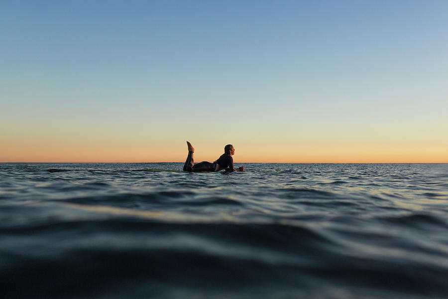 Side View Of Woman Lying On Surfboard In Sea During Sunset Photograph ...