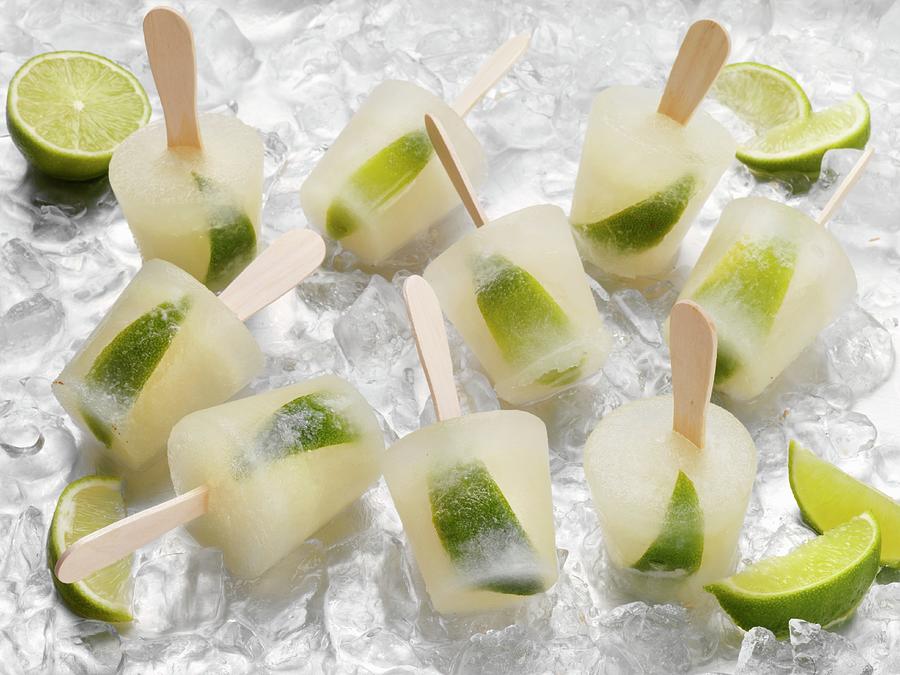 Tequila And Lime Ice Lollies On A Bed Of Ice Cubes #1 Photograph by Stuart Macgregor