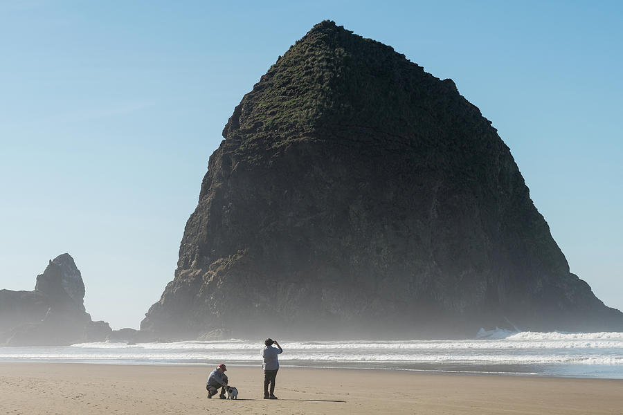 Tourists With A Dog  Enjoying The Beach With Haystack Rock In Thcannon Beach, Oregon, Usa - October Photograph