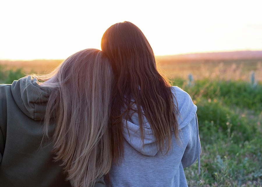 Two Girls Back To Back Watching The Sunset #1 by Cavan Images