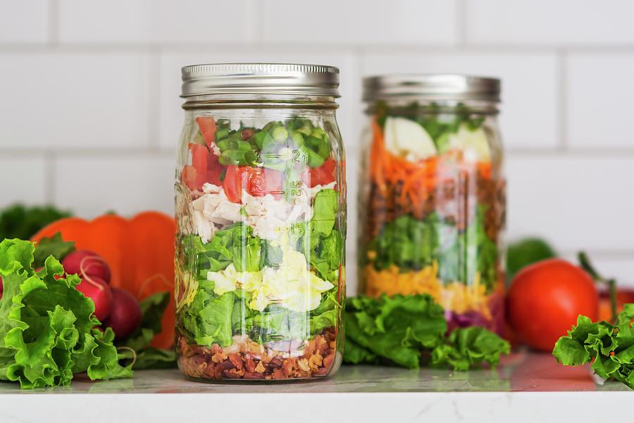 Two Layered Salads In Glass Jars With Spinach, Beans, Cheese And Eggs #1 Photograph by Brian Enright