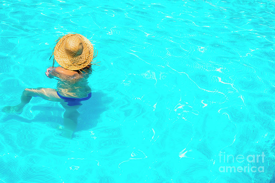 Woman in a pool with hat relaxed and rested. #1 Photograph by Joaquin Corbalan