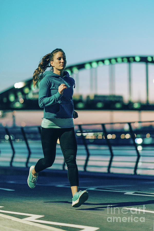 Woman Jogging In City At Night #1 by Microgen Images/science Photo Library