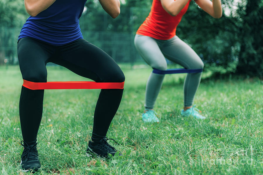 Women Exercising With Elastic Bands In A Park #1 Photograph by Microgen Images/science Photo Library