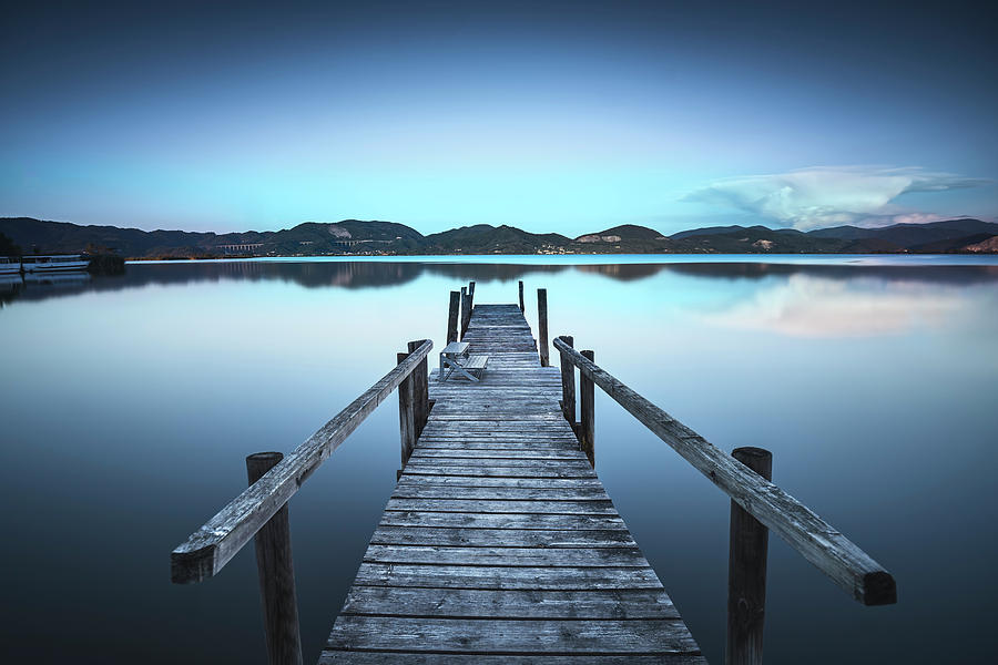 Wooden pier or jetty on a blue lake sunset and sky reflection on Photograph by Stefano Orazzini