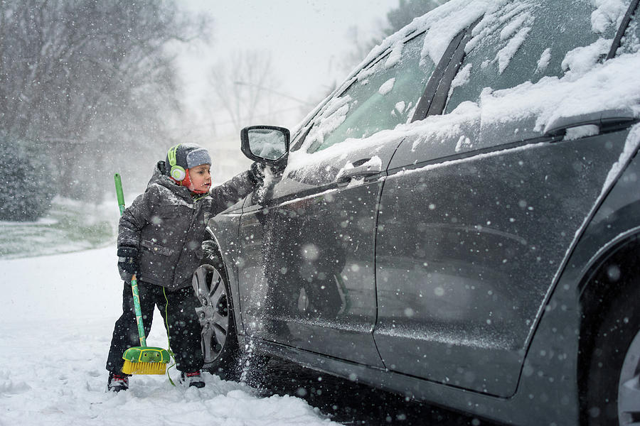 Young Boy In Gray Jacket Brushing Snow Off Gray Car On Snowy Day ...