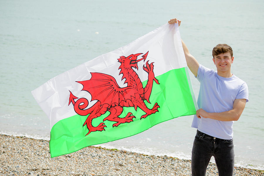 Caucasian male on a beach holding a Welsh flag by Ben Gingell Caucasian male on a beach holding a Welsh flag by Ben Gingell