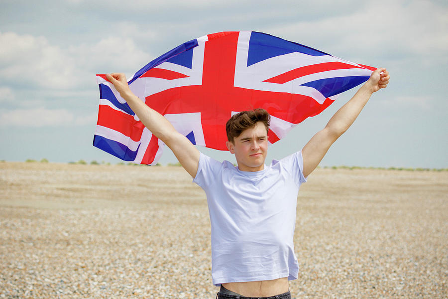 Caucasian male on a beach holding a British flag by Ben Gingell Caucasian male on a beach holding a British flag by Ben Gingell