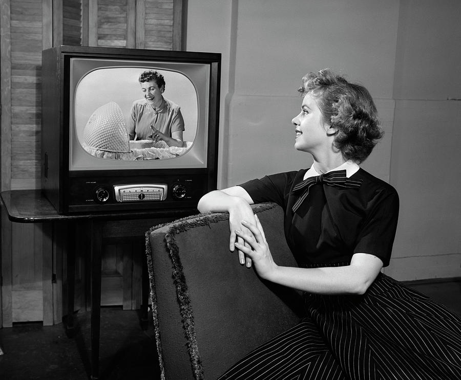 charming retro woman sitting on vintage suitcase and tv set while