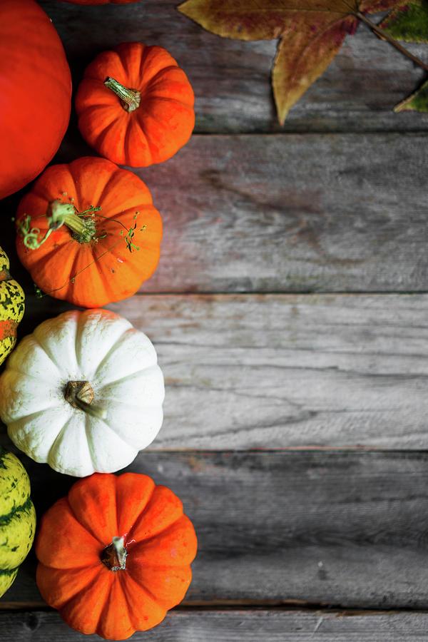 Bright Pumpkins And Autumn Leaves On Rustic Wooden Surface #2 Photograph by Alena Haurylik