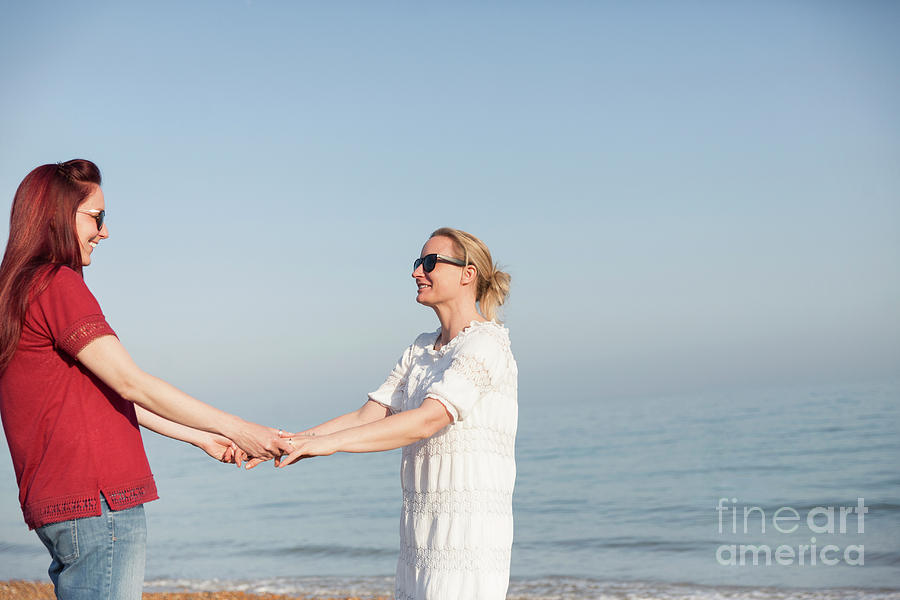 Lesbian Couple Holding Hands On Ocean Beach Photograph By Caia Image
