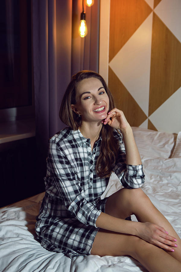 Young Girl In Plaid Shirt Sitting On A Big Bed At Home Photograph