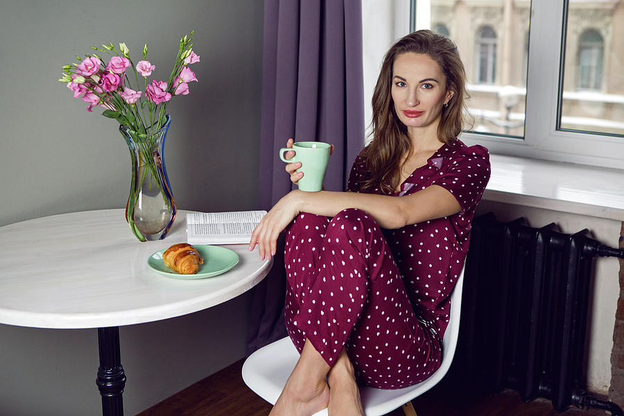 young woman in red pajamas with polka dots sitting at Breakfast Photograph