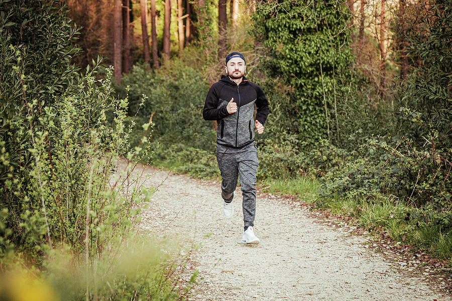 Man In Cap And Dark Tracksuit Running Through The Forest Photograph by ...