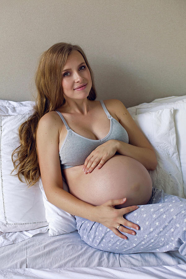 Pregnant Girl In Bra And Pants Sitting On Bed #3 Photograph by